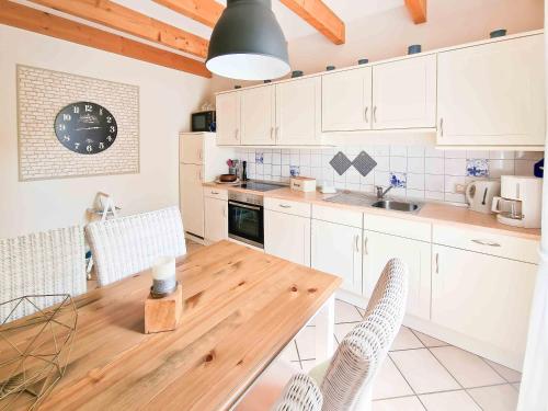 诺登Am Sommerdeich的厨房配有木桌和白色橱柜。