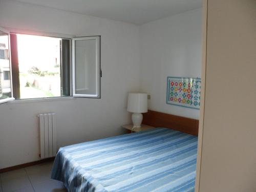 蓬塔阿拉Appartamento 109 - Multiproprietà I Boboli BC的一间卧室设有一张床和一个窗口