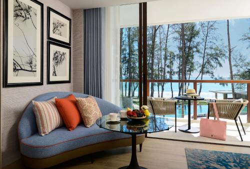 卡马拉海滩InterContinental Phuket Resort, an IHG Hotel的客厅配有蓝色的沙发和桌子