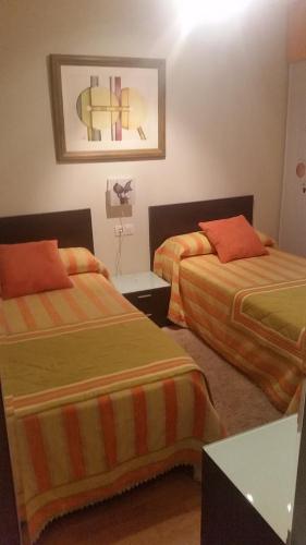 桑亨霍Apartamento Carabuxeira 1的酒店客房设有两张床和一张桌子。