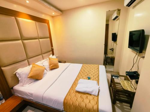 孟买Apex Hotel的一间卧室配有一张带两个枕头的床和电视。