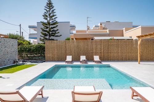 马斯蒂查里Villa Eos Mastichari - with heated pool的后院的游泳池,带椅子和围栏