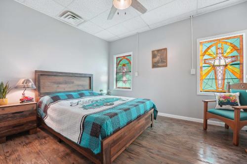 OmahaOld Church Retreat with Fire Pit and Air Hockey!的一间卧室配有一张床、一把椅子和彩色玻璃窗
