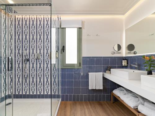 巴塞罗那H10大学酒店的浴室铺有蓝色瓷砖,配有淋浴。