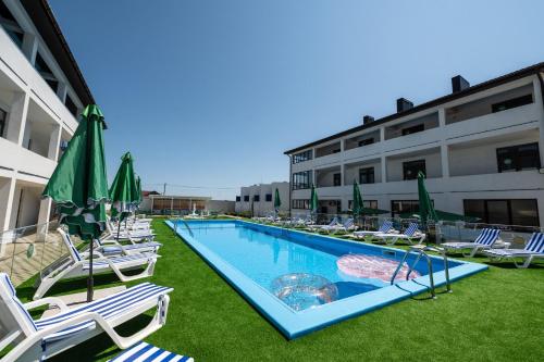 卡罗利诺-布加兹Weekend Family Hotel的一个带草坪椅和遮阳伞的游泳池