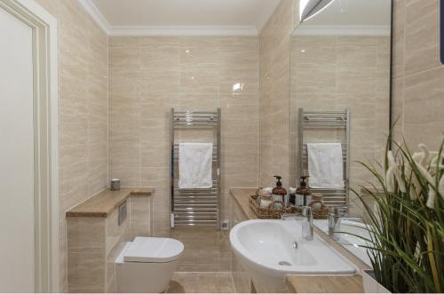 GoodmayesLight Airy Double Short walk from Elizabeth Line的浴室配有盥洗盆、卫生间和浴缸。