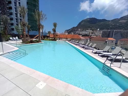 直布罗陀BRAND NEW - Studio Apartments in EuroCity - Large Pool - Rock View - Balcony - Free Parking - Holiday and Short Let Apartments in Gibraltar的一个带椅子的游泳池,背景是山脉