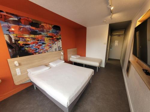 达迪利KYRIAD DIRECT LYON NORD - Dardilly的卧室配有一张床,墙上挂有绘画作品