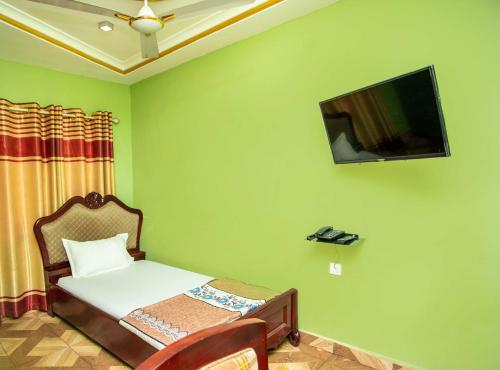 库马西Glory Hills Hotel的卧室配有一张床,墙上配有电视。