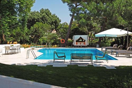 拉格尼西Villa Oasis with Large Pool Athenian Riviera Lagonissi的游泳池设有长椅、桌子和遮阳伞