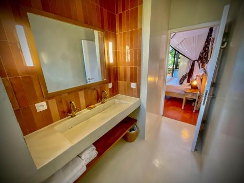 贝岛Maison Ylang Dive Center的一间带水槽和镜子的浴室以及一张床