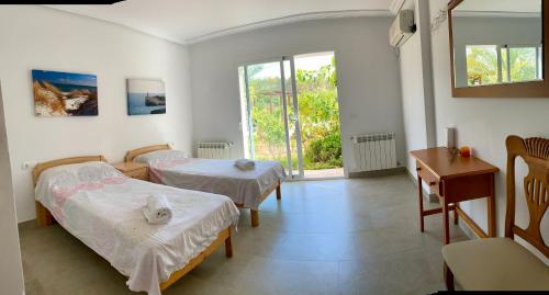圣塔格鲁迪斯Villa Can Toni Miquelí的一间卧室设有两张床、一张桌子和一个窗口