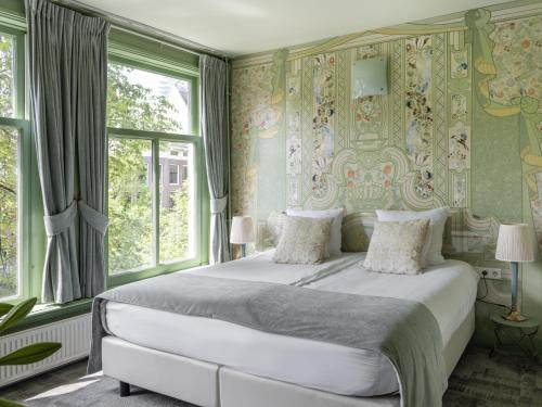 阿姆斯特丹T酒店的一间卧室设有一张大床,拥有绿色的墙壁和窗户。