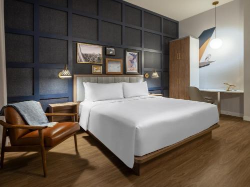 法拉盛voco Fiorello - LaGuardia East, an IHG Hotel的卧室配有一张白色大床和一把椅子