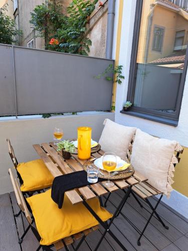 波尔图Boavista Luxury Villas的阳台的一张带黄色枕头的木桌