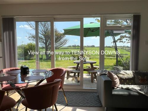 淡水VALLEY VIEW self-catering coastal bungalow in rural West Wight的客房设有桌椅和大窗户。