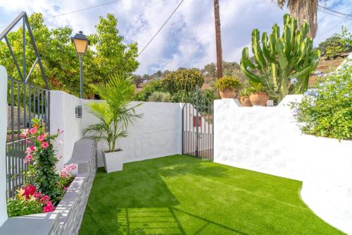 内尔哈Casa Higuera的花园设有白色的围栏和绿色的草地