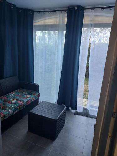 圣西普里安Logement plage的客房设有床和带蓝色窗帘的窗户。