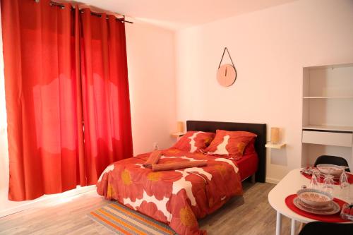 圣康坦Saturne的一间卧室配有红色窗帘、一张床和一张桌子