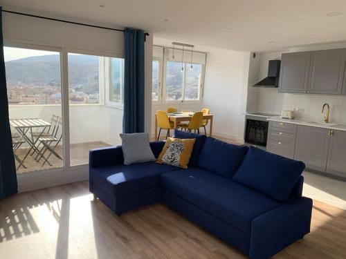 阿尔么丽亚ATICO PASEO DE ALMERÍA的一间带蓝色沙发的客厅和一间厨房