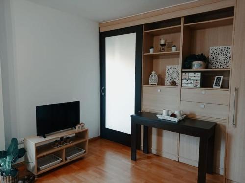 韦斯卡Acogedor apartamento con piscina y garaje的客厅配有桌子和电视