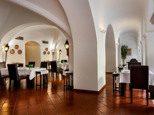 阿尔维图卡斯特洛阿尔维托酒店的用餐室配有白色桌子和黑色椅子