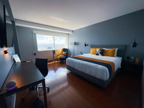托卢卡Hotel Opus Grand Toluca Aeropuerto的一间卧室配有一张床、一张书桌和一个窗户。