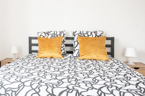 米卢斯L'Escapade Mulhousienne的一间卧室配有黑色和白色的床,提供两个橙色枕头