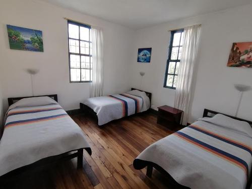 基多加拉帕戈斯自然生活旅舍的配有白色墙壁和木地板的客房内的两张床
