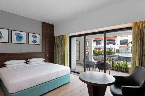 比纳里姆Fairfield by Marriott Goa Benaulim的一间卧室配有一张床铺和一张桌子,并设有一个阳台