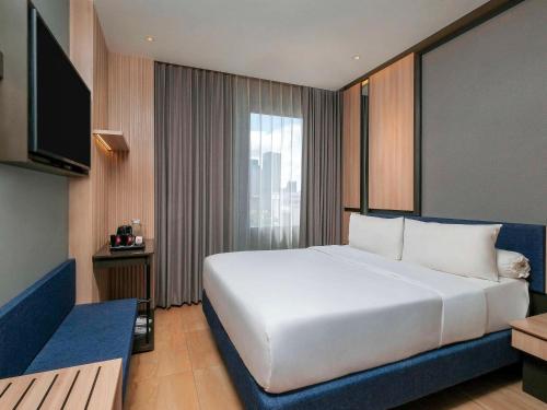 泗水ibis Surabaya Tidar的卧室配有一张白色大床和电视。