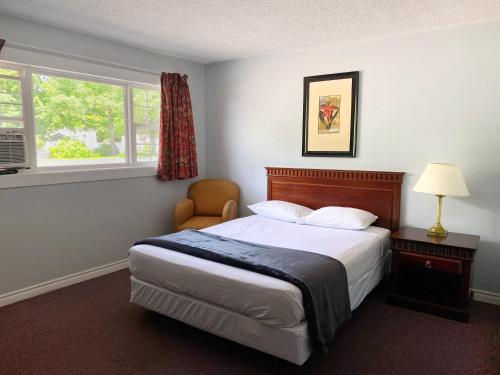 弗雷德里克顿纳斯瓦克堡垒汽车旅馆的一间卧室配有一张床和一把椅子,还有两个窗户