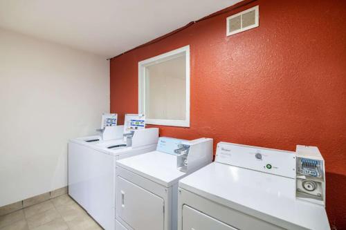 佩科斯Rodeo Inn的一间设有3台洗衣机和橙色墙壁的房间
