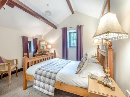 Gilcrux伯温班克乡村别墅的一间卧室配有一张床和一张带台灯的桌子