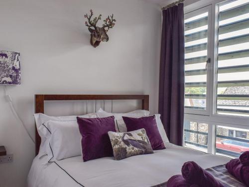 GrampoundBluebell Barn的一间卧室配有一张带紫色枕头的床和窗户。