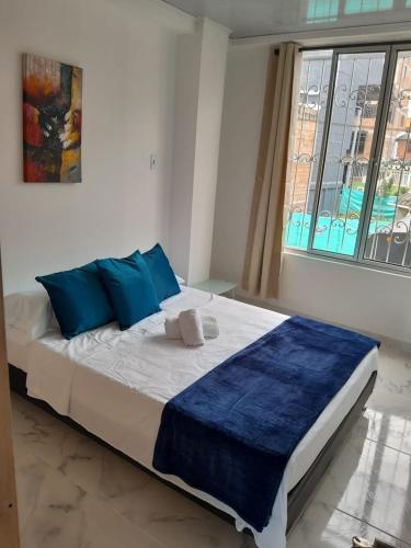 圣罗莎德卡瓦尔Apartamento Amoblado en la via Termales Santa Rosa de Cabal的一间卧室配有一张带蓝色枕头的床和一扇窗户。