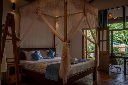 暹粒Habana Angkor Boutique Hotel的一间卧室配有带窗帘的天蓬床
