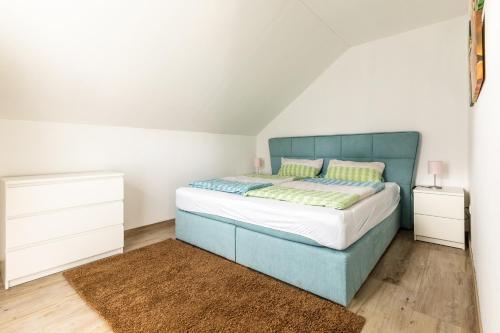 泰克伦堡Ferienwohnung Grüner Weg mit Grillplatz的一间卧室配有蓝色的床和2个床头柜