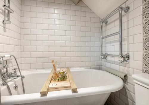雷文斯卡2 Browcote Cottage的浴室设有白色浴缸,配有木制托盘