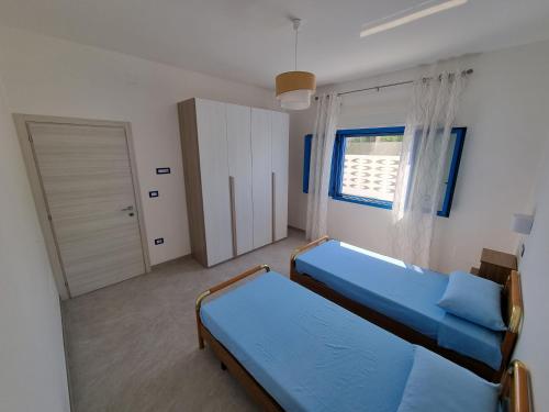 托雷拉皮罗Villetta Azzurra的一间小卧室,配有两张床和窗户