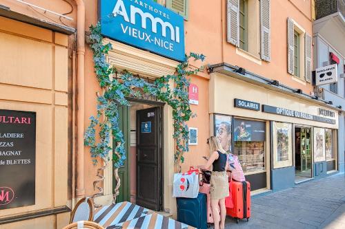 尼斯Aparthotel AMMI Vieux Nice的站在装有行李的商店前的妇女