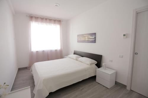 博瓦利诺马里纳La Suite del Borgo的白色的卧室设有白色的床和窗户。