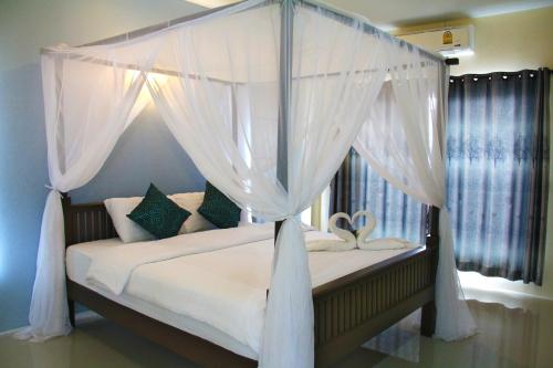 素可泰素可泰蓝屋酒店的卧室配有带白色窗帘的天蓬床