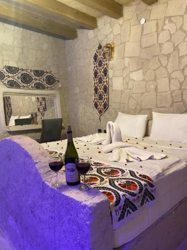 格雷梅Seven Rock Cave Hotel的一间卧室配有一张带两杯葡萄酒的床