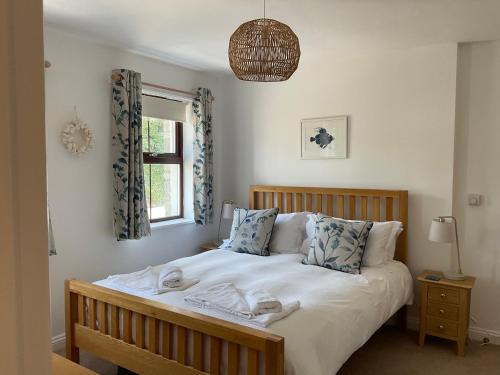 卡兰斯拓克Sunnyside Cottage的一间卧室配有一张带白色床单的床和一扇窗户。