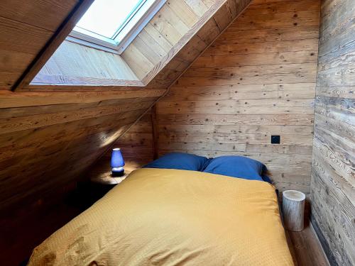 莱鲁斯Chalet Vieux Bois, au coeur du village des Rousses的木制客房的一张床位,设有窗户