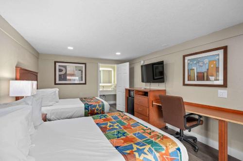 奥兰多Travelodge by Wyndham Kissimmee Orlando的酒店客房配有两张床和一张书桌