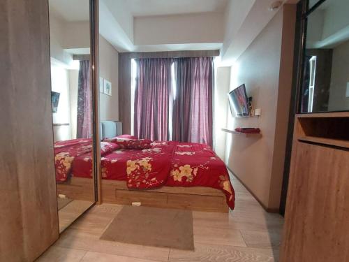 西冷Ilham Apartemen Batch 1的一间卧室配有红色的床和镜子