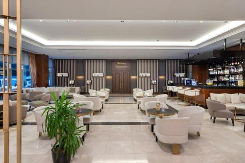 伊斯坦布尔Miracle Istanbul Asia Airport Hotel & Spa的一间设有白色桌椅的餐厅和一间酒吧
