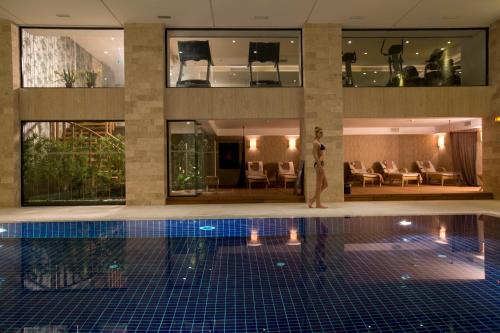 伊斯坦布尔Miracle Istanbul Asia Airport Hotel & Spa的站在一座建筑物游泳池旁的人